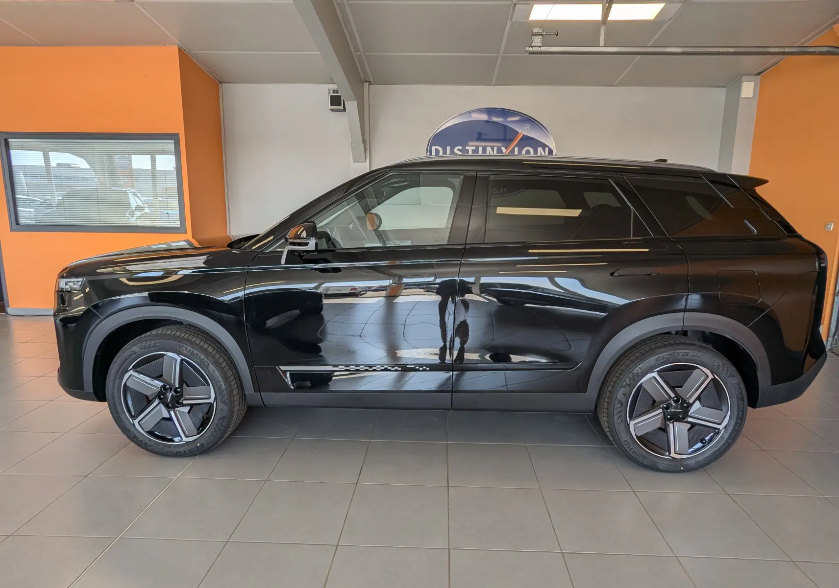 Vue de profil côté gauche du SUV JAECOO J7 hybride rechargeable noir carbone métal, avec jantes modernes et lignes épurées.