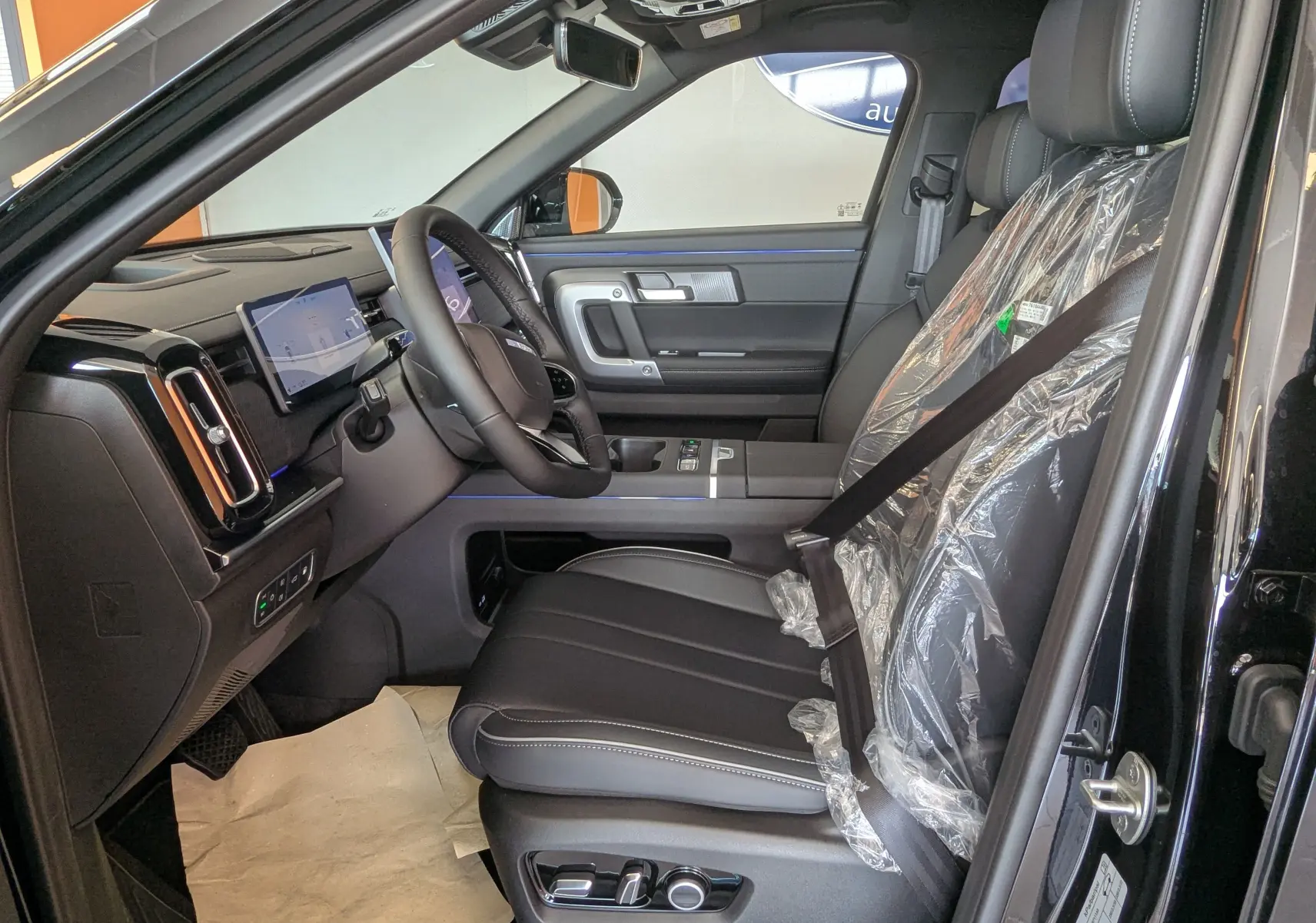 Intérieur côté conducteur du JAECOO J7 noir carbone, sièges cuir protégés, tableau de bord digital et volant multifonction.