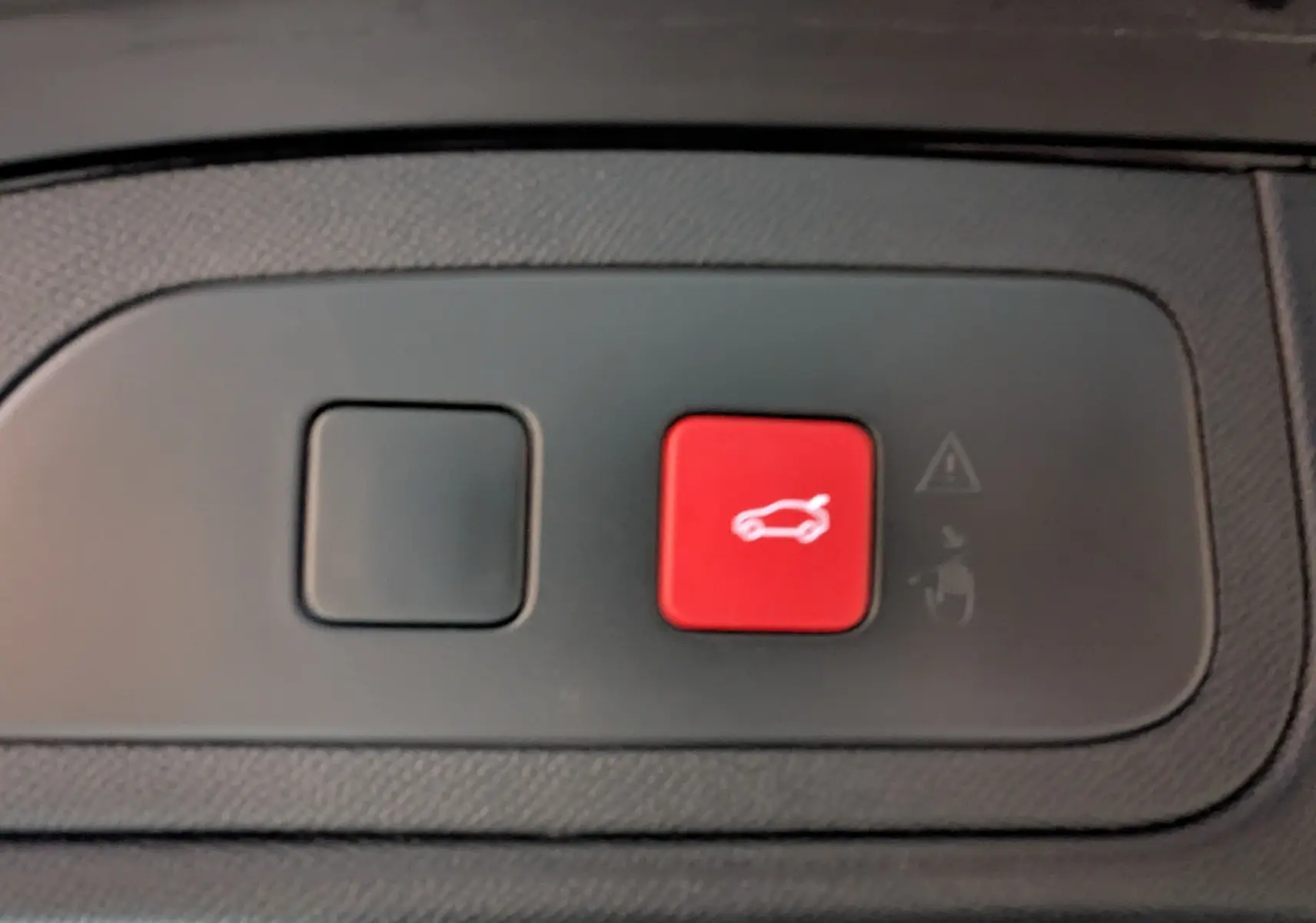 Gros plan sur bouton rouge d'ouverture du hayon électrique dans l'habitacle du DS7 gris laqué 2025.