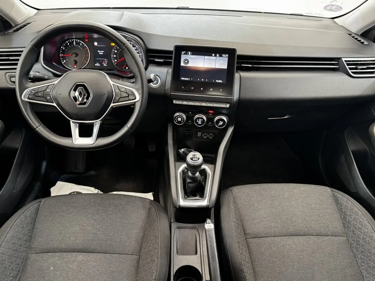 Vue intérieure frontale de la Renault Clio Business TCe 90 2020, tableau de bord noir avec écran tactile et volant multifonctions.