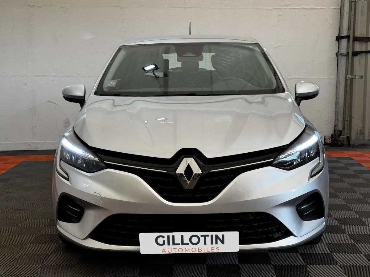 Vue frontale d'une Renault Clio Business TCe 90 gris clair avec feux LED allumés dans un garage.