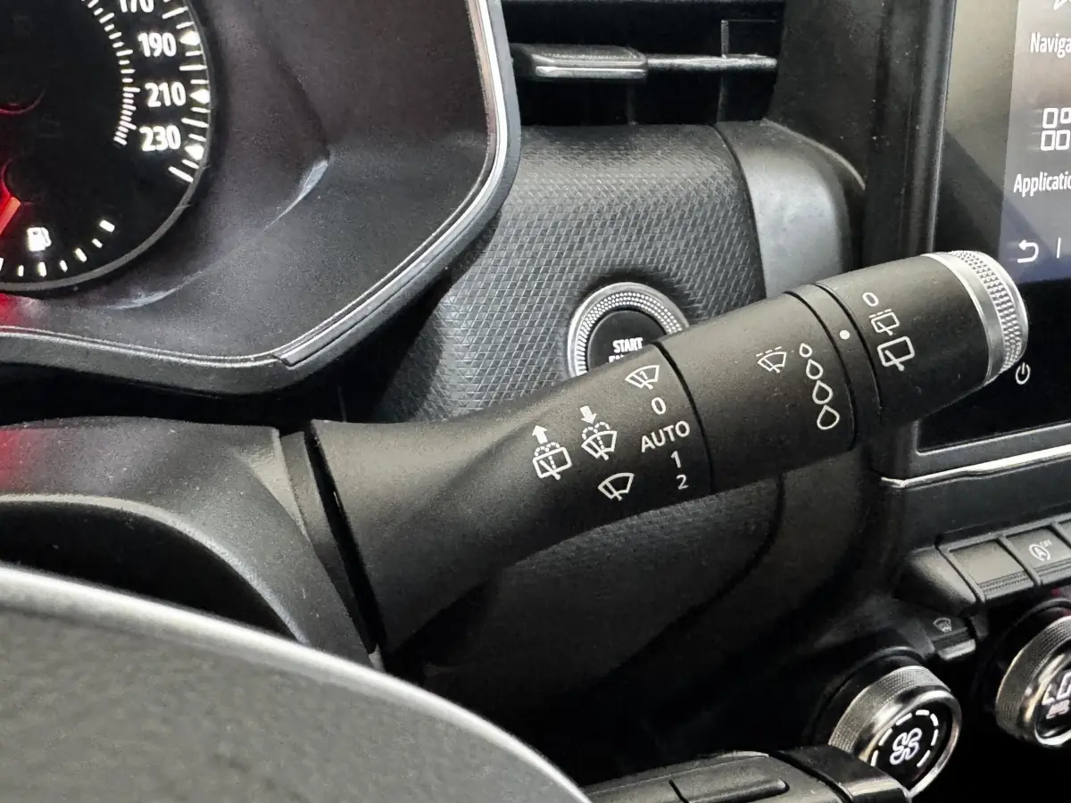 Gros plan sur la commande d’essuie-glace à gauche du volant dans l’habitacle noir de la Renault Clio Business TCe 90 gris clair.