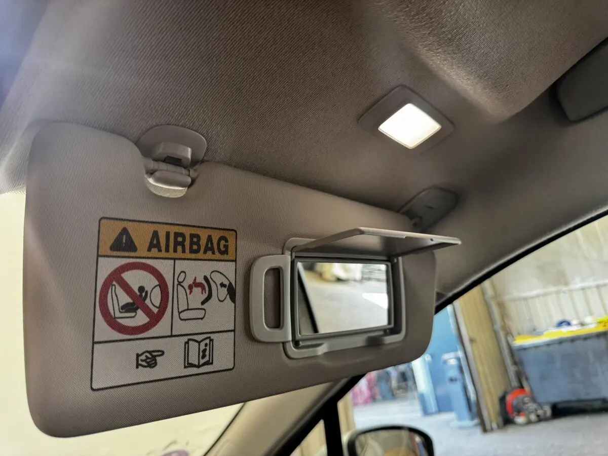 Vue intérieure côté conducteur sur le pare-soleil gris clair avec miroir et avertissement airbag éclairé.