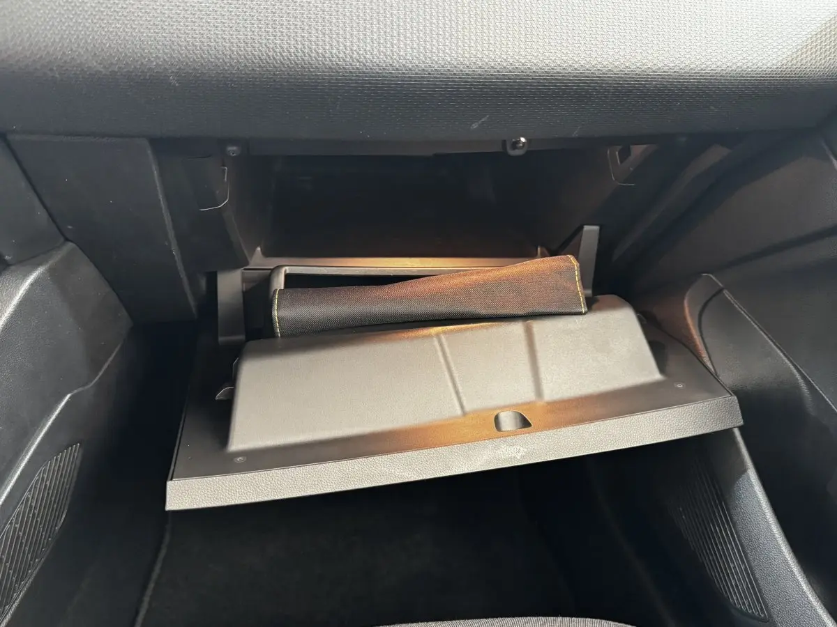 Gant de boîte à gants ouvert dans l'habitacle noir d'une Renault Clio Business TCe 90 gris clair, vue côté passager.