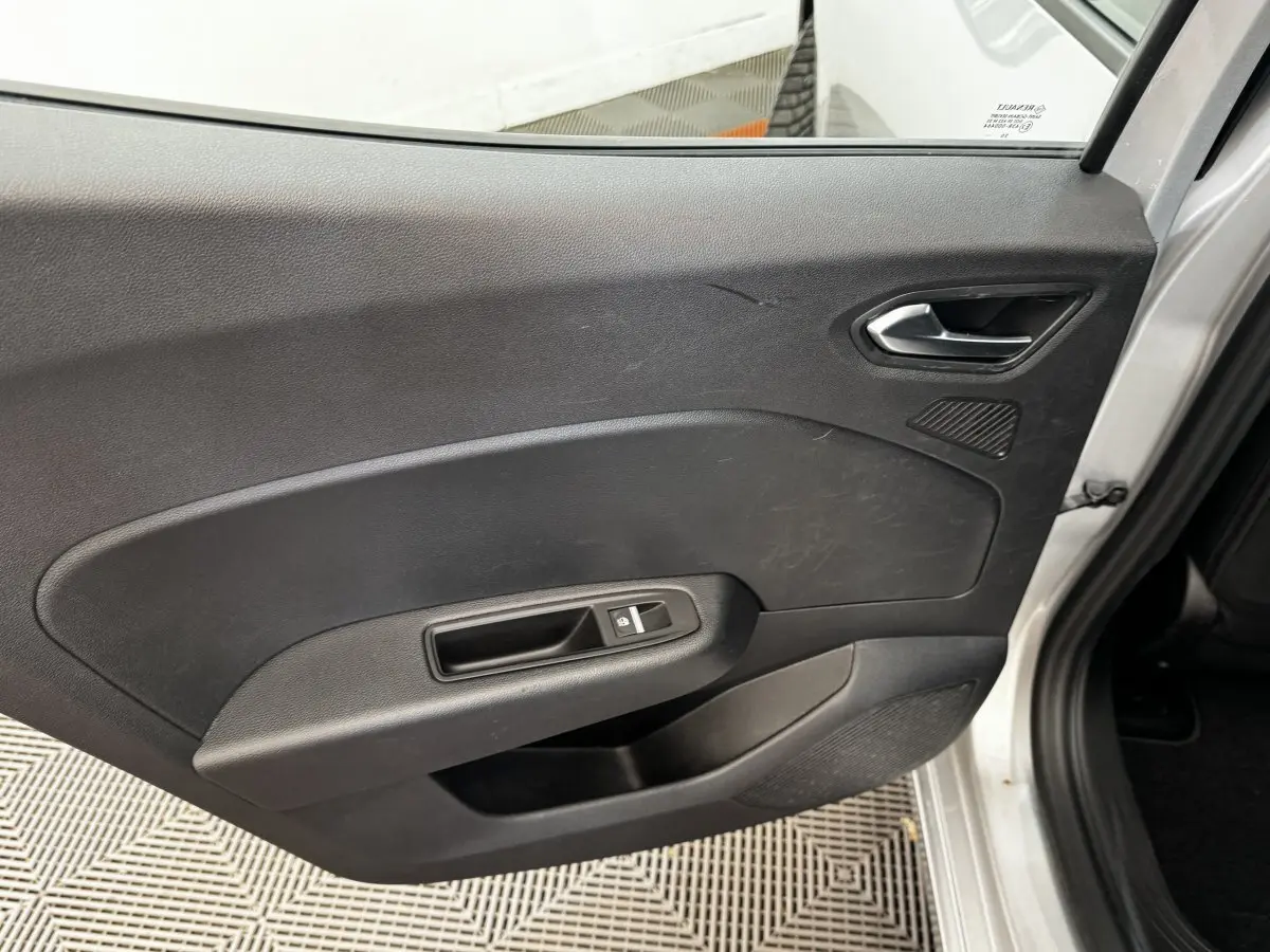 Vue intérieure côté droit de la porte arrière grise claire de la Renault Clio Business TCe 90 avec poignée et commande de vitre électrique.