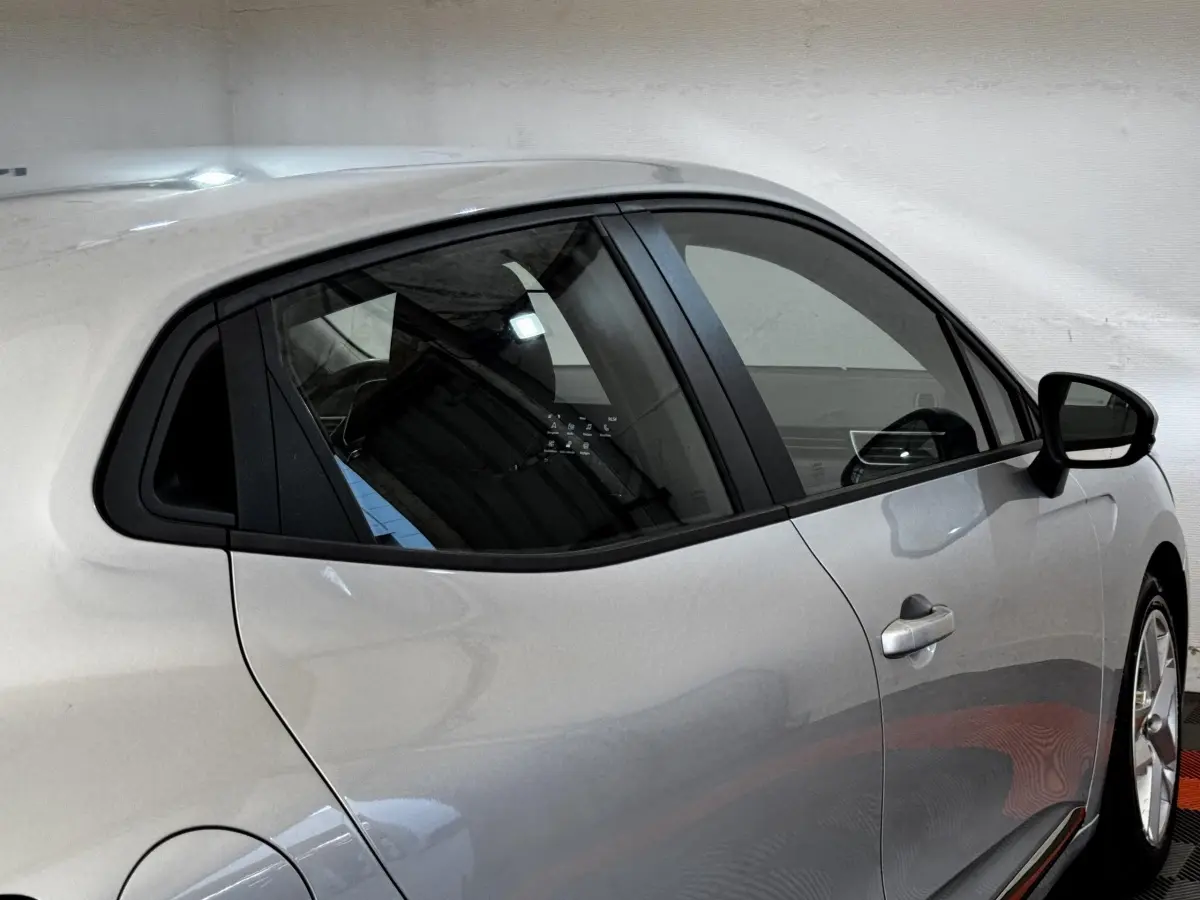 Profil droit d'une Renault Clio Business TCe 90 gris clair, avec poignées de porte intégrées et vitres teintées.