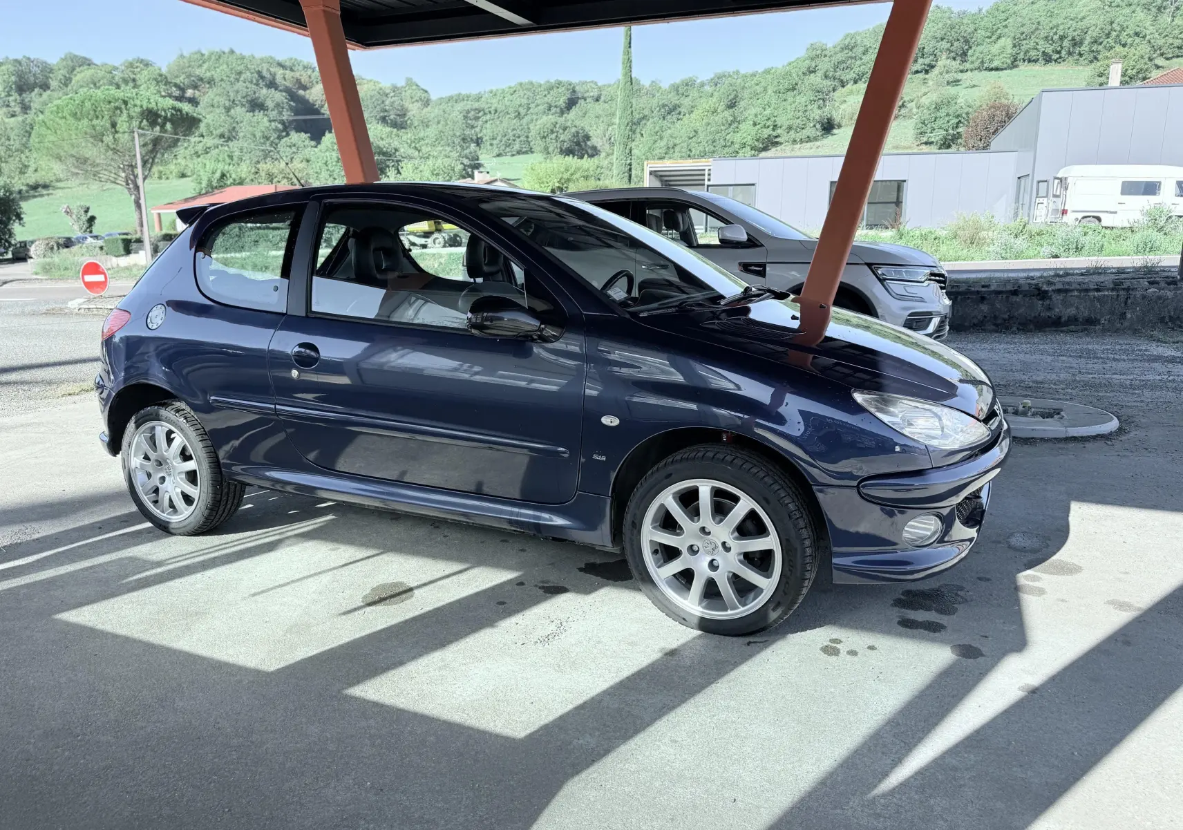 Peugeot 206 bleu en vue latérale droite sous abri, avec jantes alliage et carrosserie compacte trois portes.
