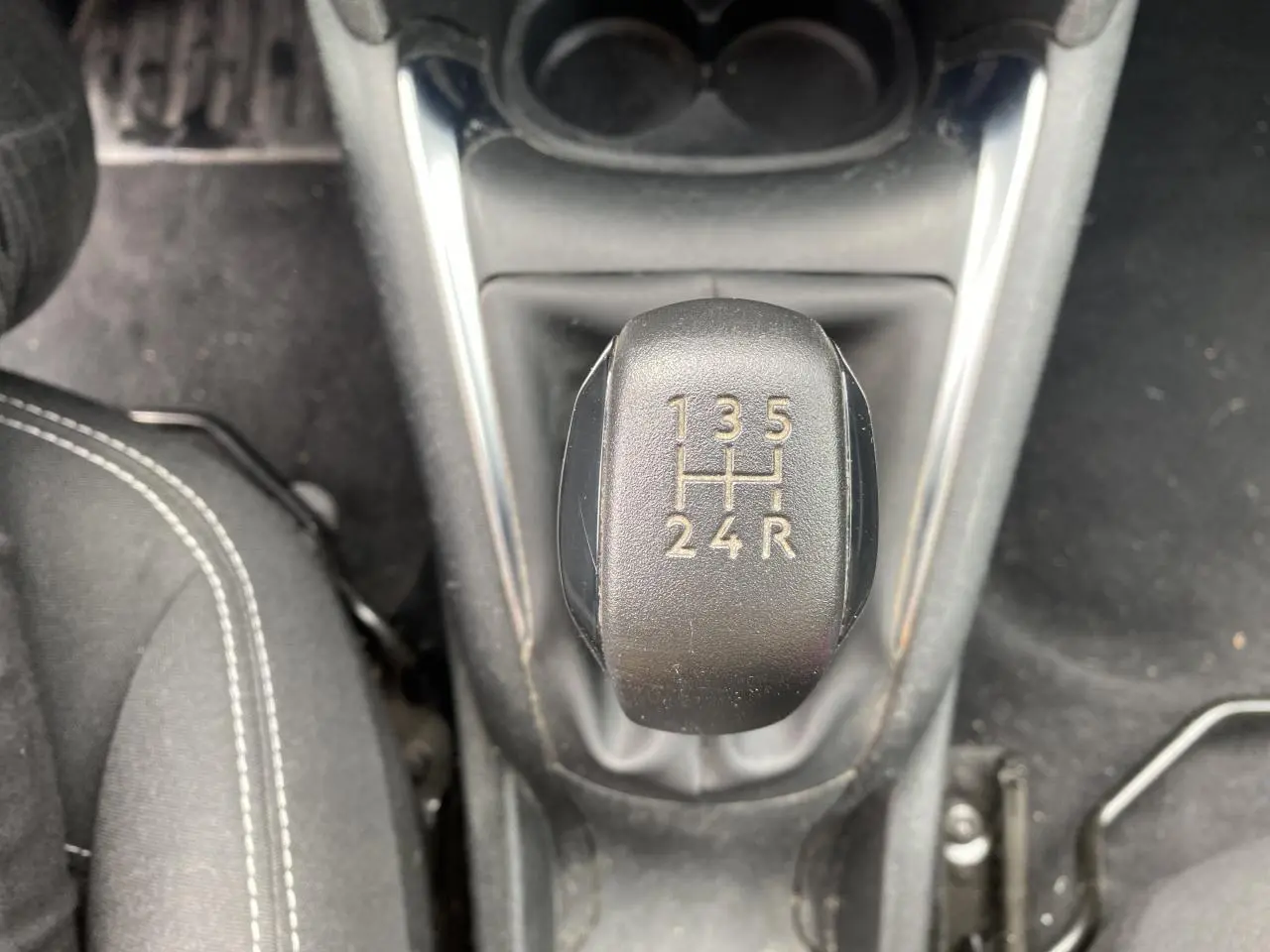 Le levier de vitesses manuel noir de la Peugeot 208 gris, vu de dessus avec coutures blanches sur les sièges.