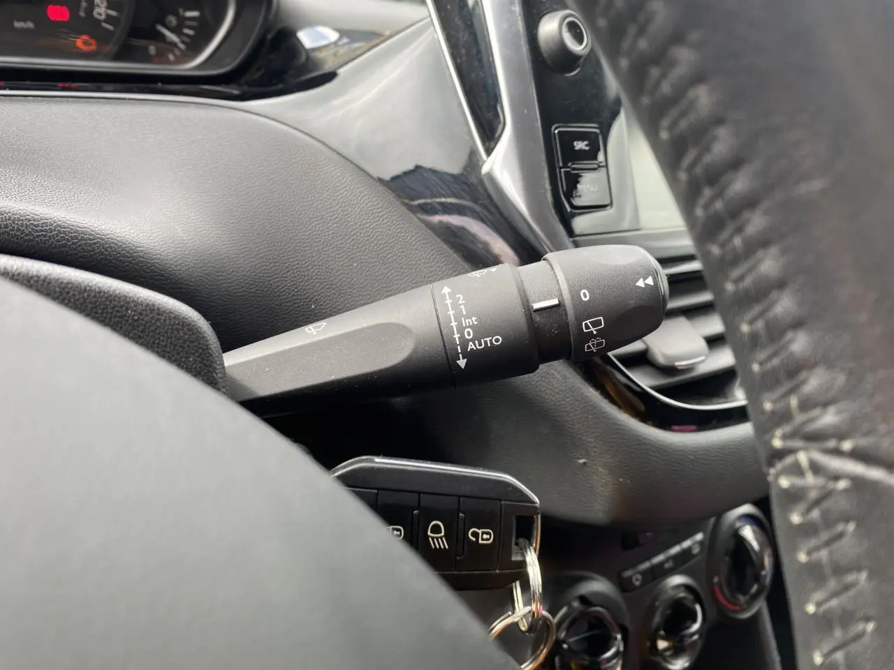 Gros plan sur la manette d'essuie-glace et le tableau de bord noir d'une Peugeot 208 gris 2018, version Active Business.