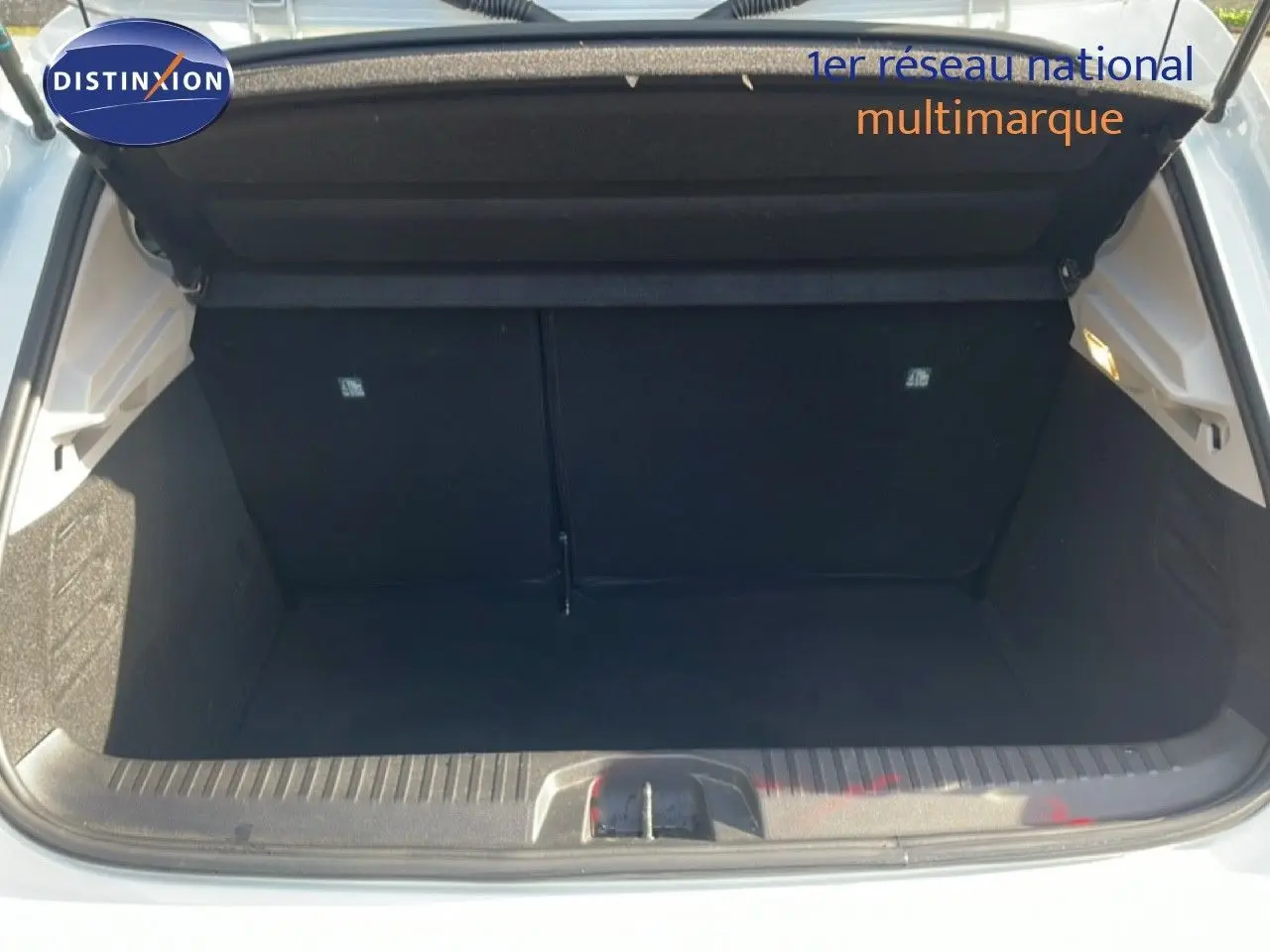 Coffre ouvert d'une Renault Clio blanc glacier, vue arrière montrant l'espace de chargement vide et propre.