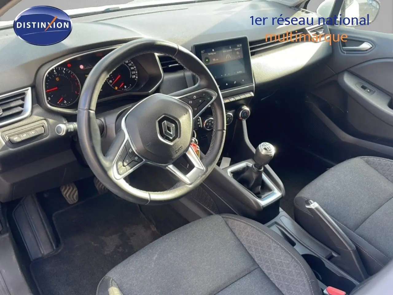 Intérieur de Renault Clio 2021 vue côté conducteur, tableau de bord moderne avec boîte manuelle et sièges tissu gris.