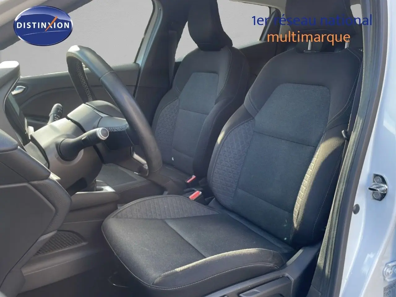 Vue intérieure côté conducteur de la Renault Clio blanche glacier 2021, sièges tissu gris noir et volant visible.