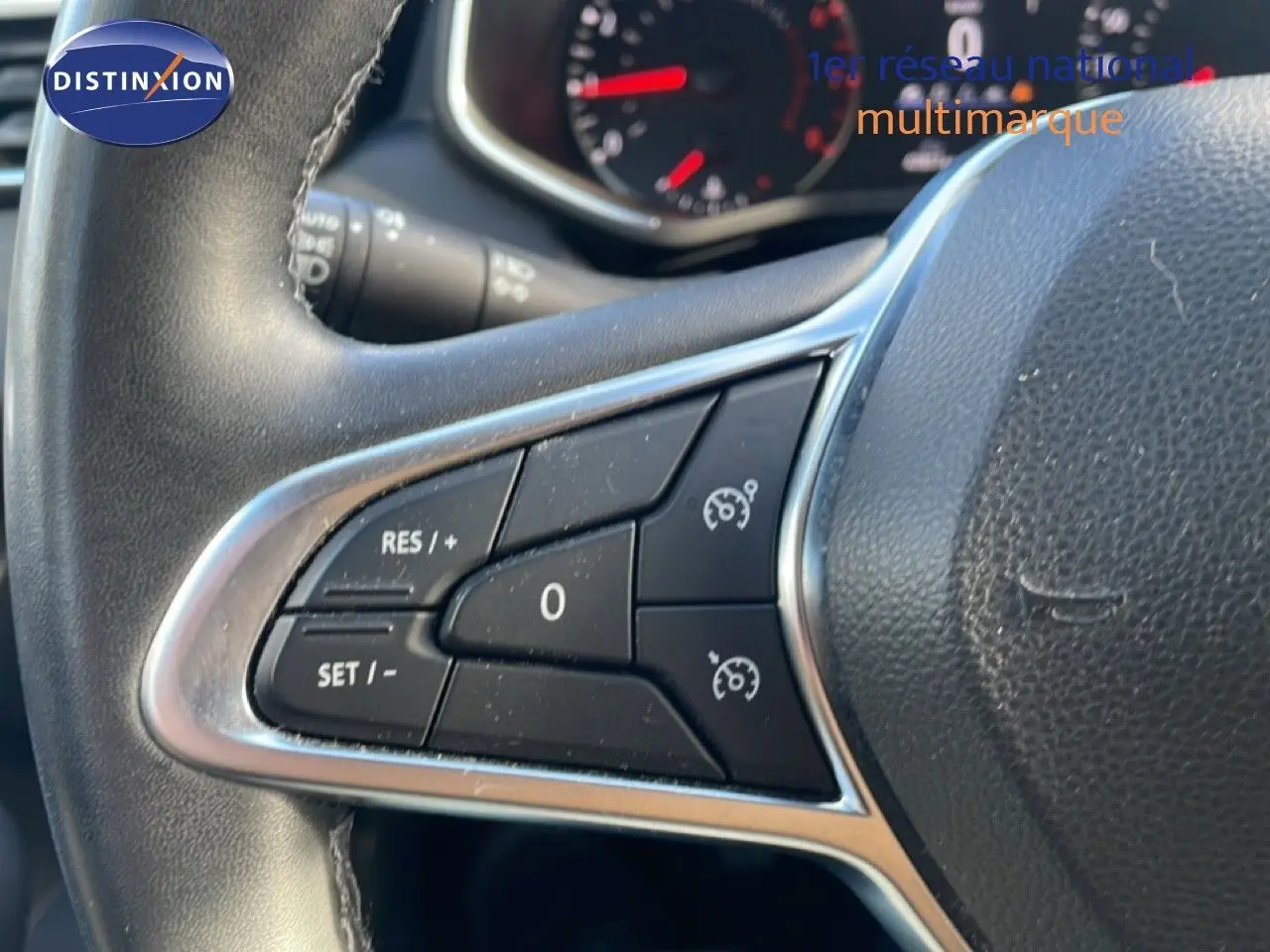 Gros plan sur les commandes de régulateur de vitesse à gauche du volant d'une Renault Clio blanc glacier 2021.