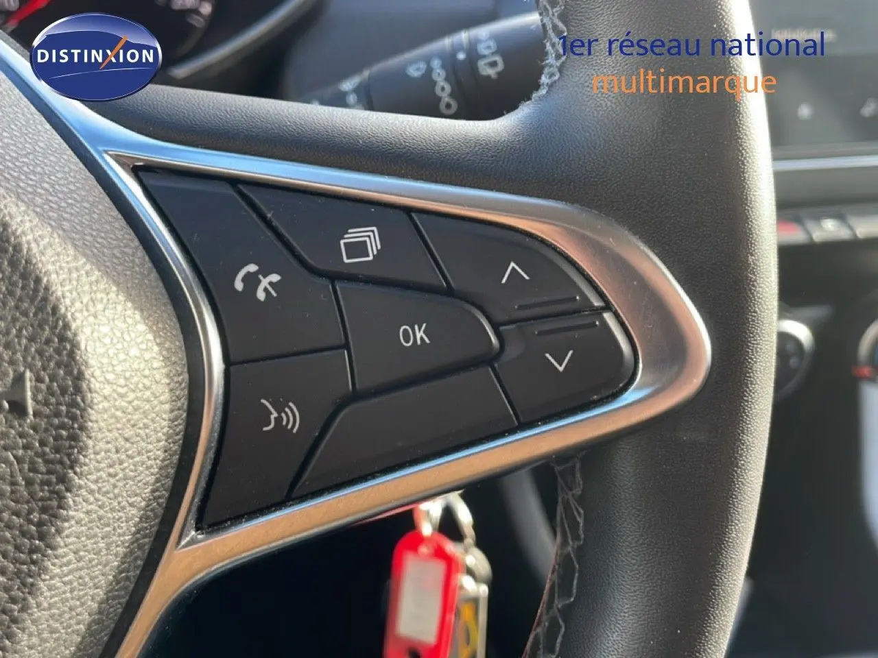 Gros plan sur les commandes au volant d'une Renault Clio blanche glacier 2021, avec boutons multifonctions et finition cuir noire.