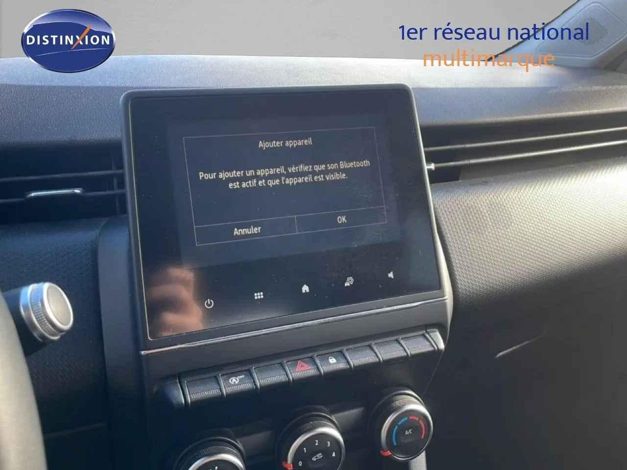 Vue rapprochée de la console centrale de la Renault Clio blanche 2021, avec écran tactile affichant la connexion Bluetooth.