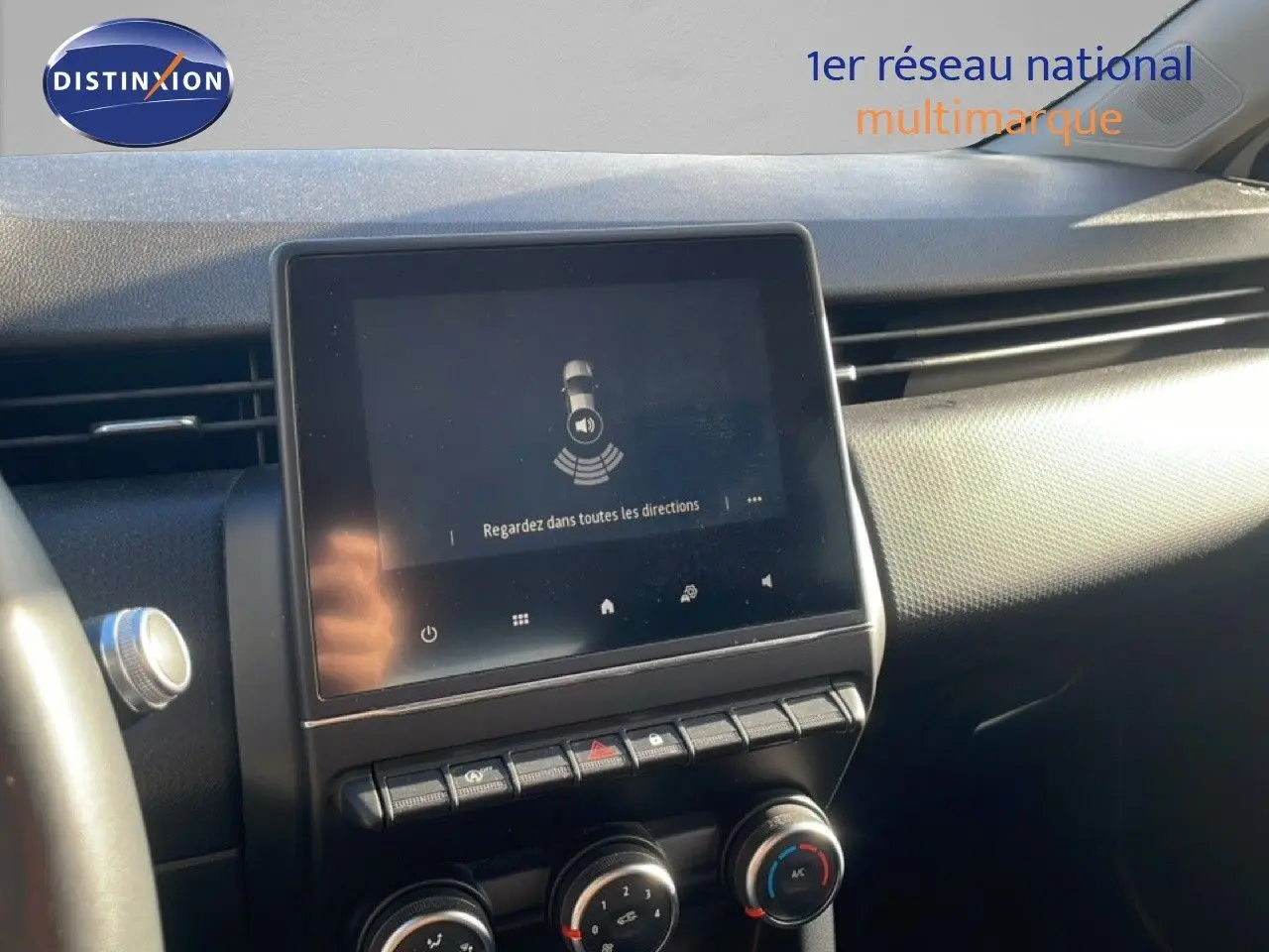 Vue rapprochée de l'écran tactile central et des commandes de climatisation dans l'habitacle d'une Renault Clio blanc glacier 2021.