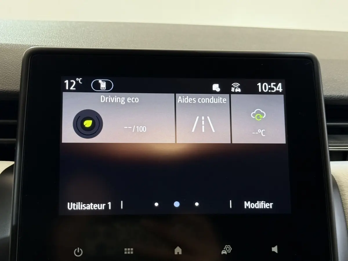 Écran tactile central de la Renault Clio blanc 2023 affichant les aides à la conduite et la température extérieure.