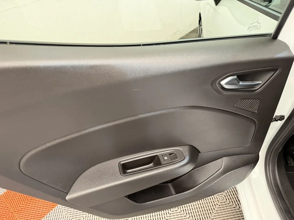 Vue intérieure sur la porte arrière droite noire d'une Renault Clio blanche, avec poignée et commande de vitre électrique.