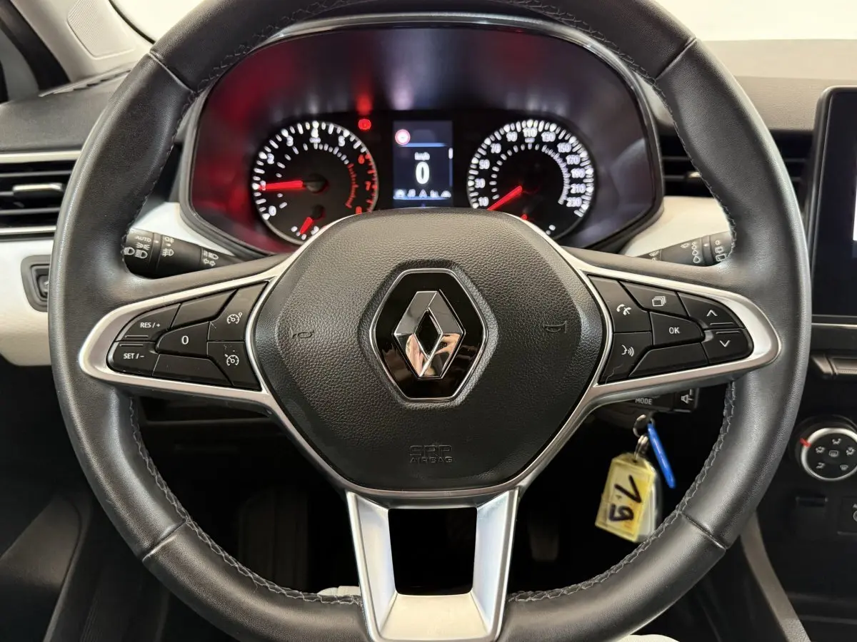 Vue rapprochée du volant cuir noir de la Renault Clio 2023 avec tableau de bord numérique et commandes intégrées.