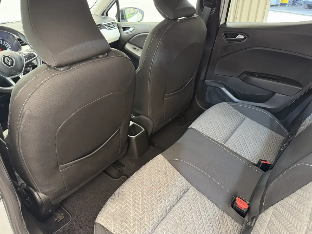 Vue intérieure arrière de la Renault Clio Evolution TCe 100 GPL 2023, sièges tissu gris et noir avec détails texturés.