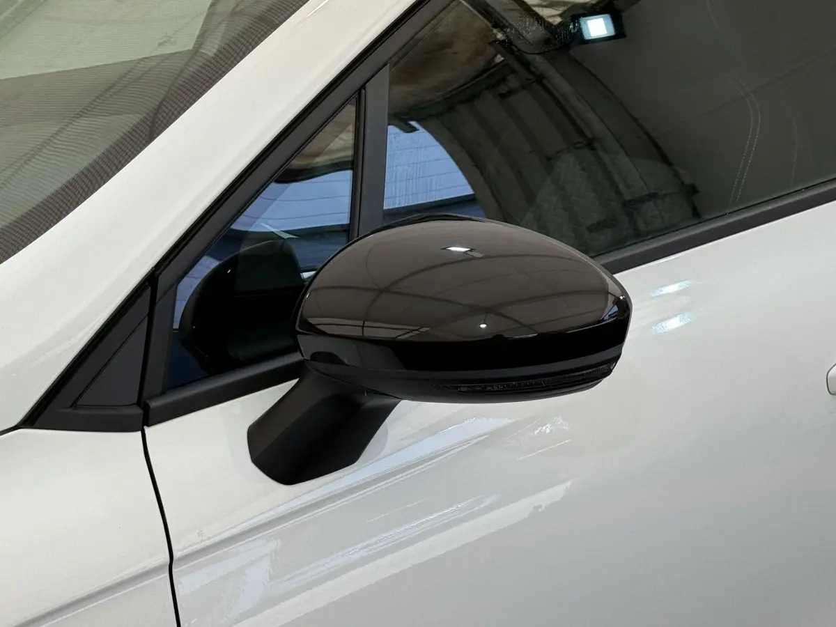 Rétroviseur noir côté gauche sur porte blanche d'une Renault Clio Evolution TCe 100 GPL 2023 vue de profil rapprochée.