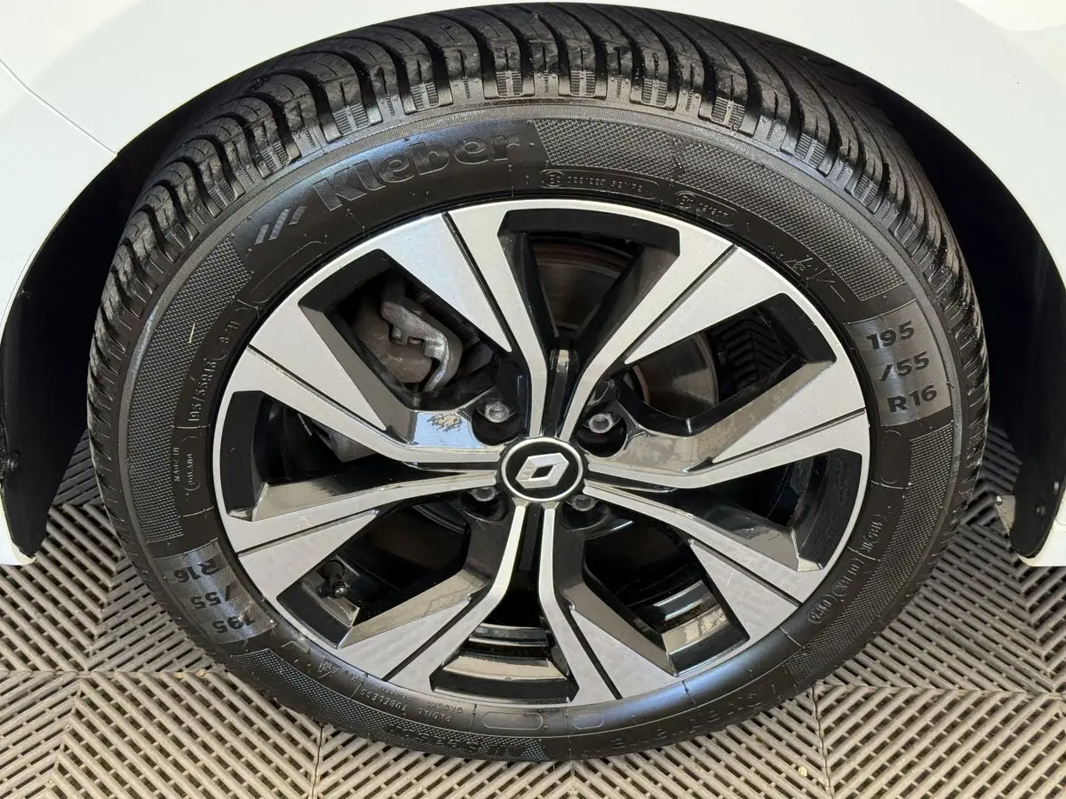 Gros plan sur la roue avant droite de la Renault Clio blanche, mettant en valeur la jante alliage bicolore et le pneu Kleber.