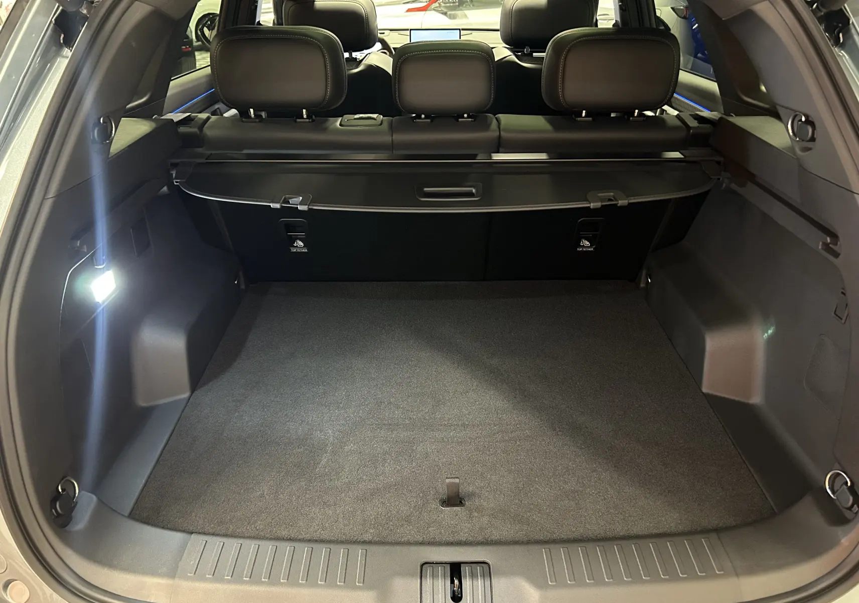 Coffre ouvert vu de l'arrière du JAECOO J7 olive grey metal, montrant un espace de chargement spacieux et banquette arrière noire.
