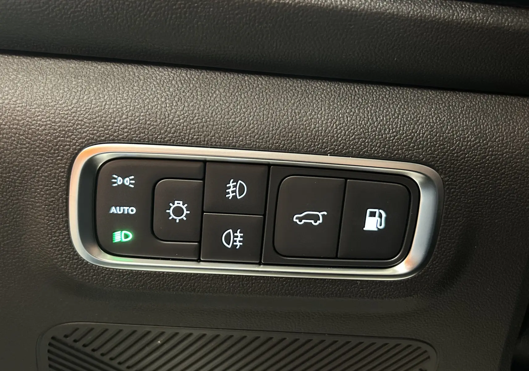 Gros plan sur les commandes d’éclairage et d’ouverture de coffre du JAECOO J7 TGDI PHEV, finition intérieure noire.