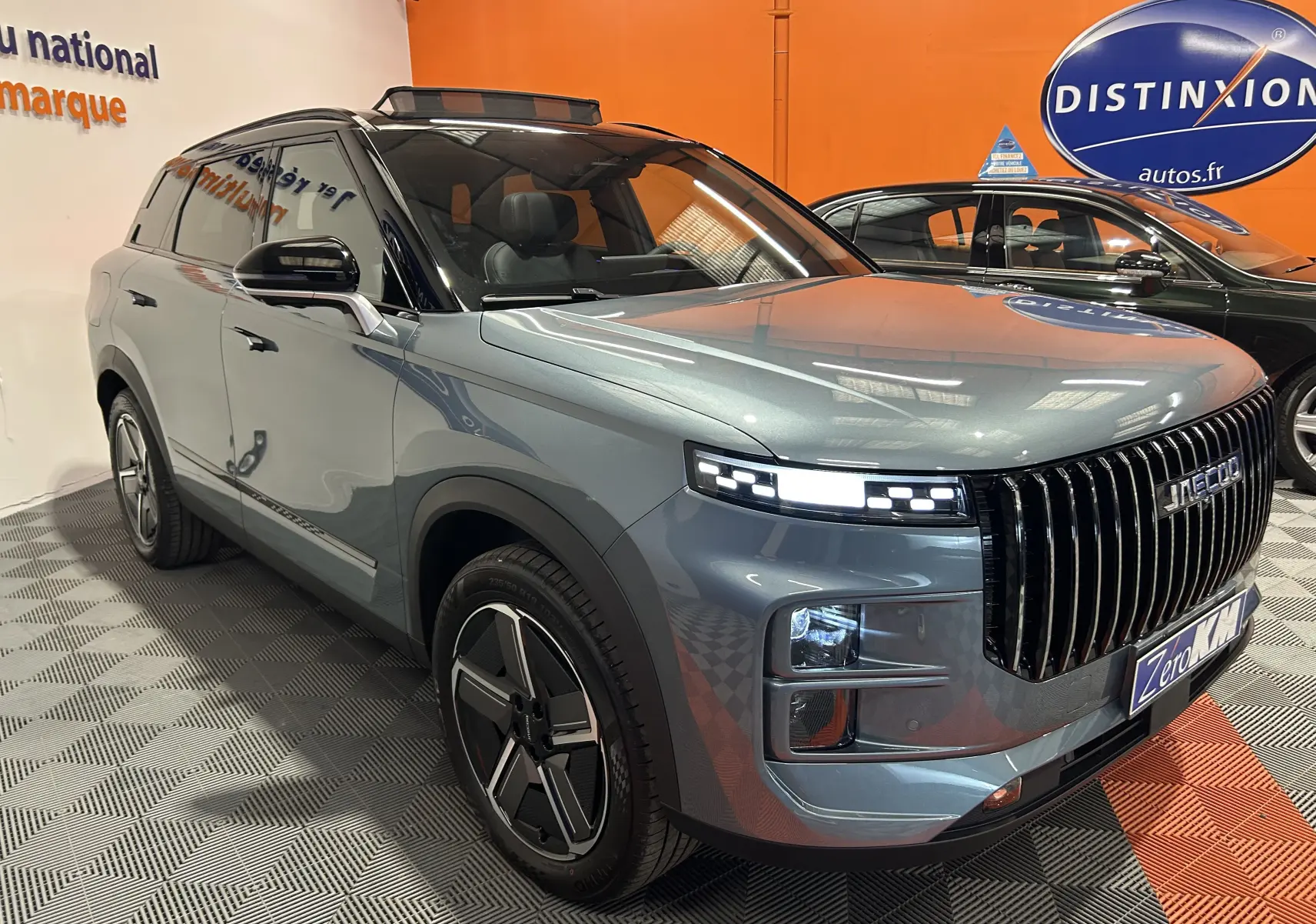 Vue 3/4 avant droite du SUV JAECOO J7 olive grey metal avec calandre verticale noire et phares LED distinctifs.