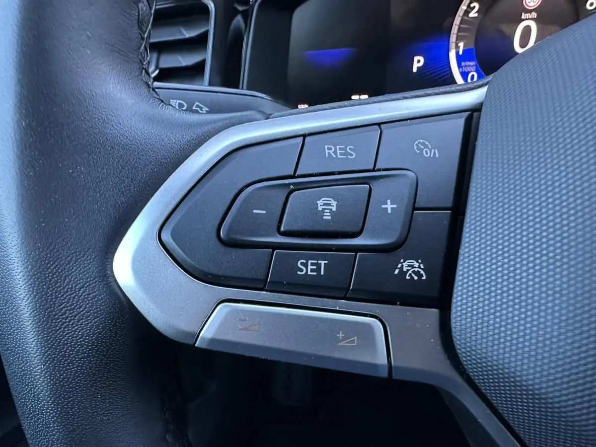 Gros plan sur les commandes de régulateur de vitesse au volant du Volkswagen Taigo 2025, intérieur noir.