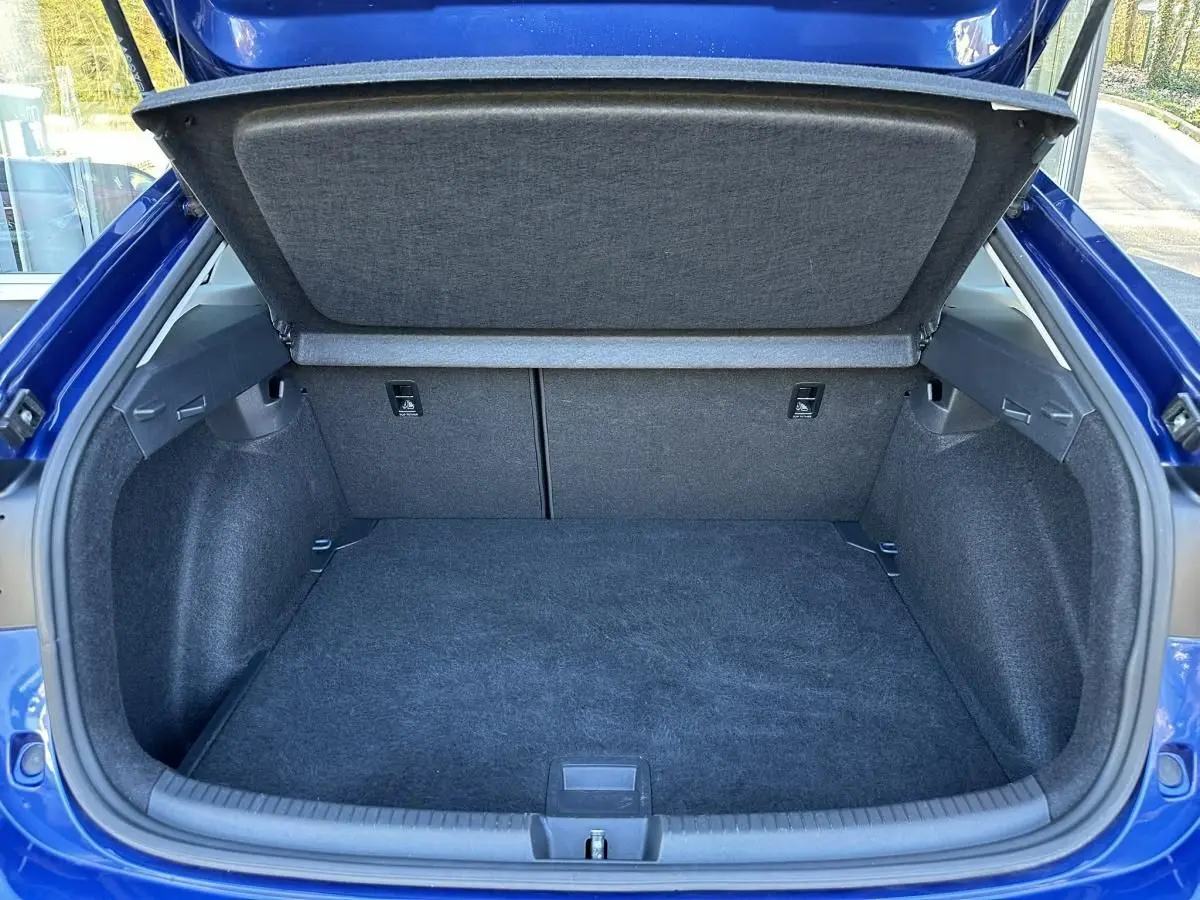 Coffre ouvert vu de l'arrière d'un Volkswagen Taigo bleu Recife, montrant un espace de chargement propre et spacieux.