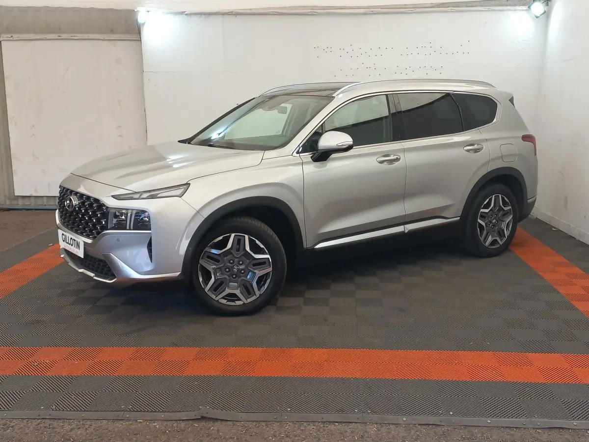 Vue 3/4 avant droite du Hyundai Santa Fe gris clair avec calandre imposante et jantes distinctives en intérieur neutre.