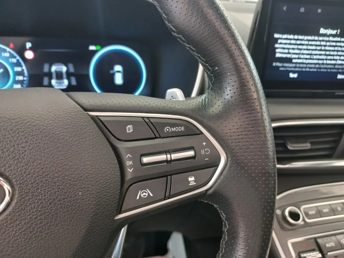 Gros plan sur le volant cuir multifonctions du Hyundai Santa Fe 2022, avec commandes de régulateur et assistance à la conduite.