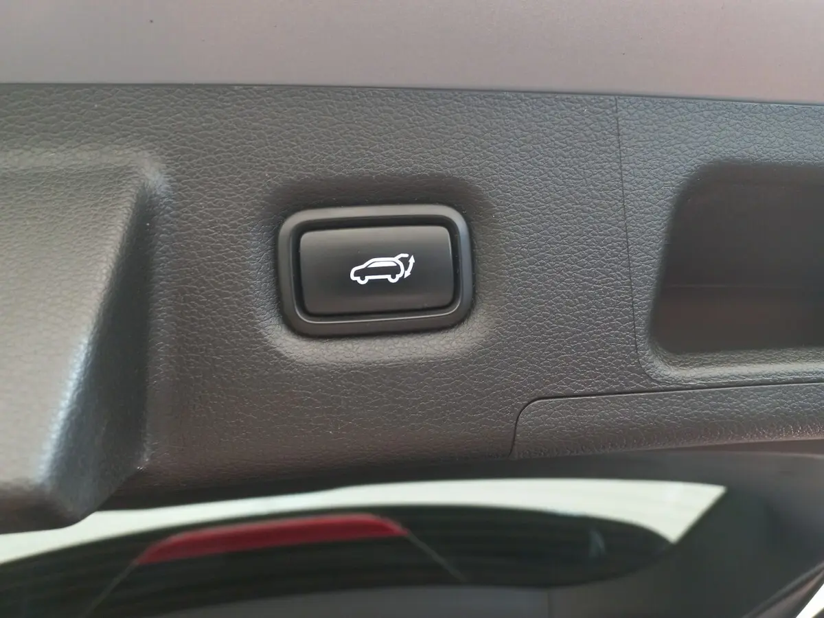 Bouton noir d'ouverture électrique du coffre sur le hayon intérieur d'un Hyundai Santa Fe gris clair.