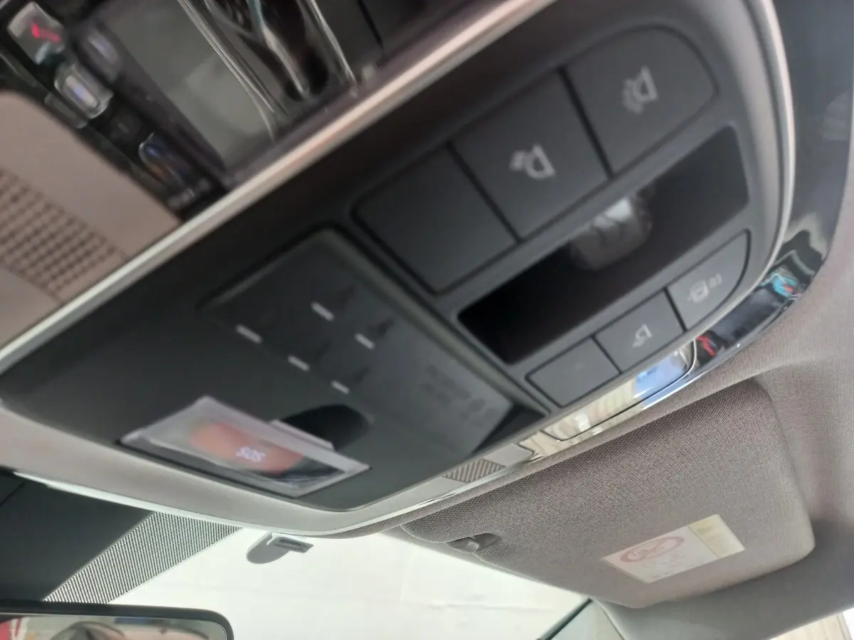 Vue intérieure en gros plan du panneau de commandes au plafond du Hyundai Santa Fe gris clair, incluant éclairages et boutons divers.
