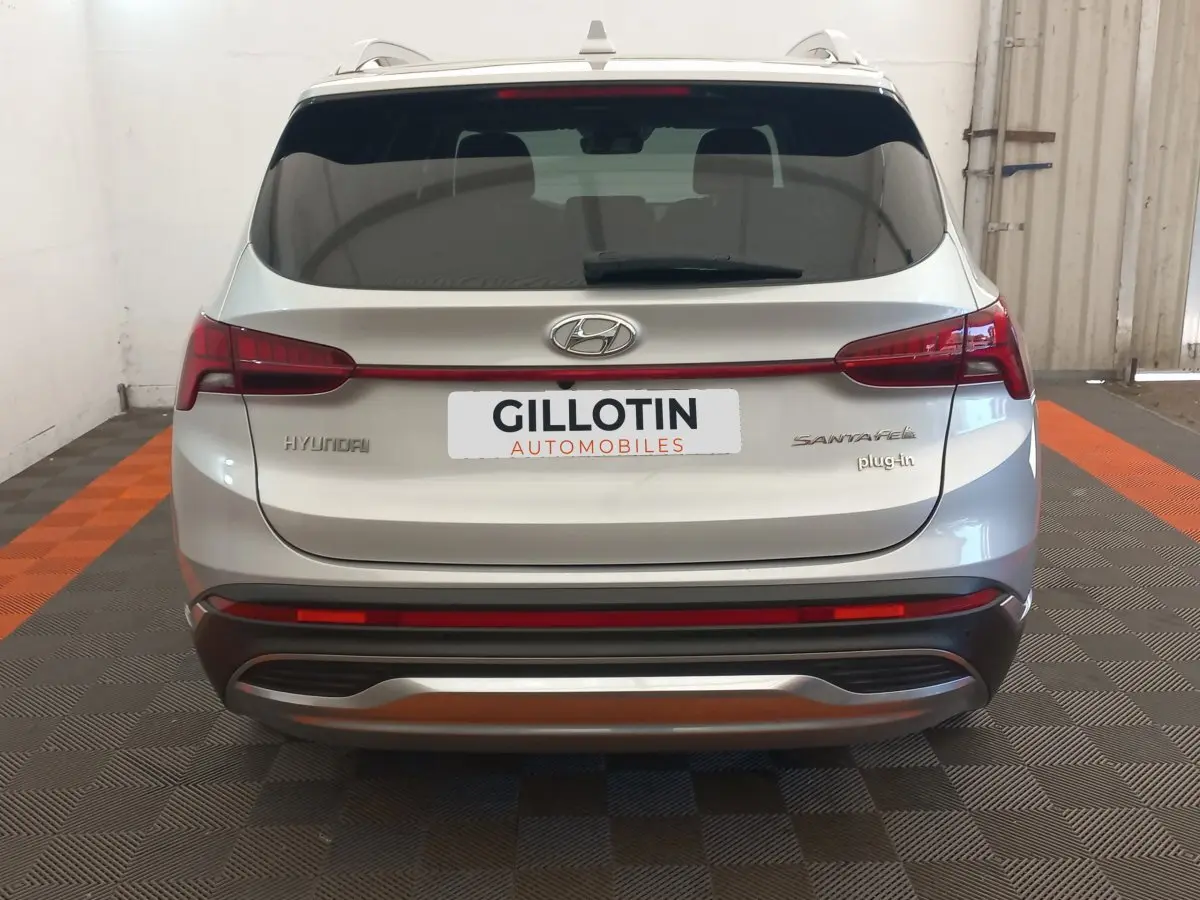 Vue arrière d’un Hyundai Santa Fe gris clair hybride rechargeable avec feux LED et logo plug-in visible.
