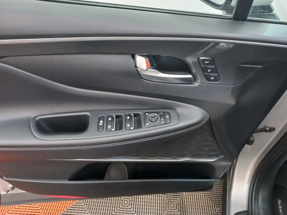 Vue intérieure côté conducteur de la porte gris clair du Hyundai Santa Fe 2022 avec commandes électriques et poignée métal.
