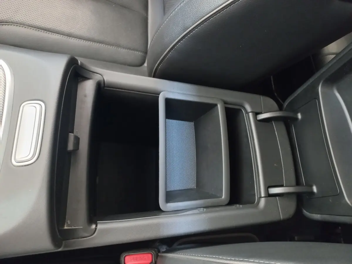 Vue rapprochée de la console centrale ouverte en plastique noir à l'intérieur du Hyundai Santa Fe gris clair 2022.