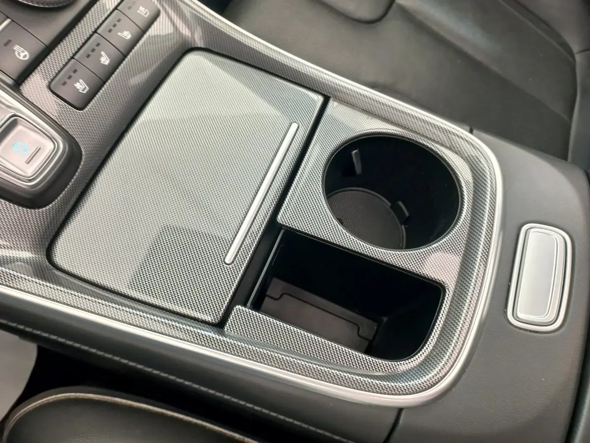 Gros plan sur la console centrale grise à effet carbone du Hyundai Santa Fe 2022, avec porte-gobelets et commandes.