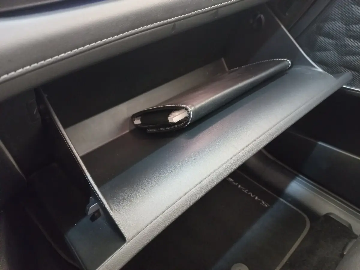 Vue intérieure du coffre à gants ouvert du Hyundai Santa Fe 2022 avec un étui noir posé à l'intérieur.