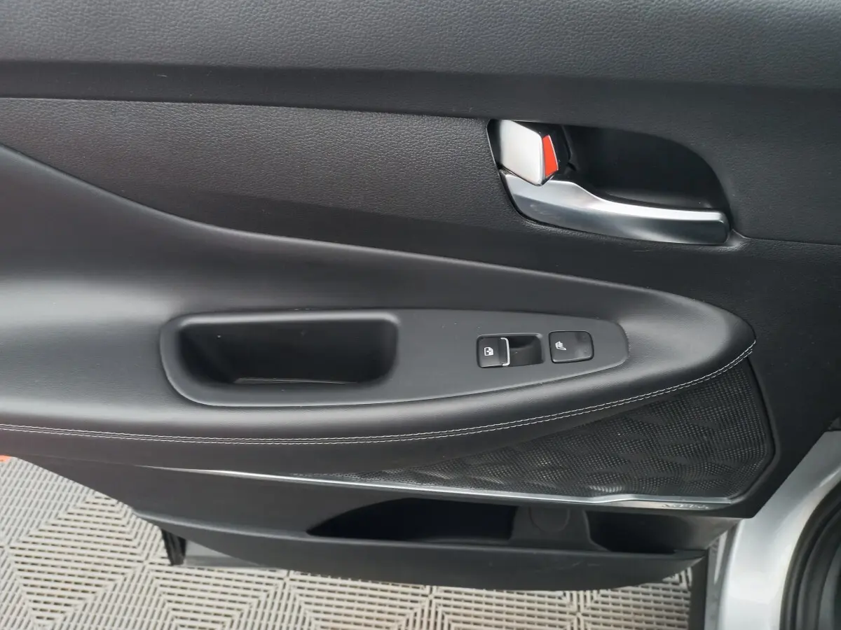 Vue rapprochée de la porte intérieure côté gauche du Hyundai Santa Fe gris clair avec commandes de verrouillage et poignée argentée.