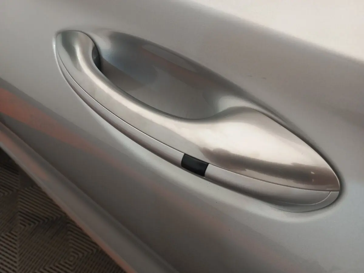 Poignée de porte côté gauche gris clair du Hyundai Santa Fe 2022, finition lisse avec bouton noir intégré.