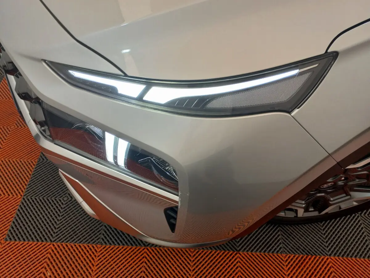 Gros plan sur l’avant droit gris clair du Hyundai Santa Fe 2022 avec phares LED allumés et calandre distinctive.