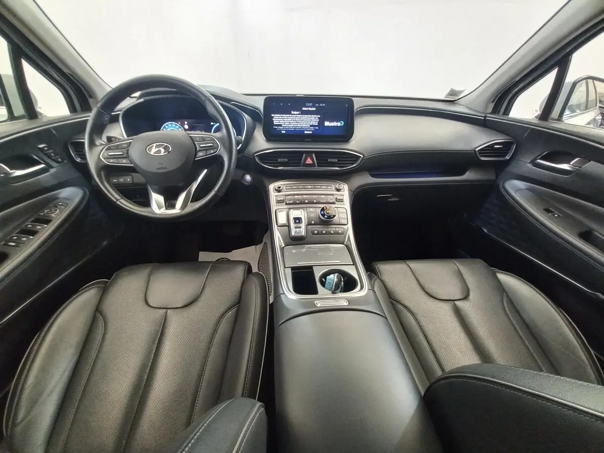 Vue intérieure avant du Hyundai Santa Fe 2022 gris clair, avec volant cuir multifonctions et écran tactile central.
