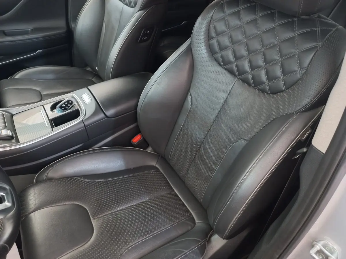 Gros plan sur les sièges avant en cuir noir matelassé du Hyundai Santa Fe gris clair, avec console centrale visible.