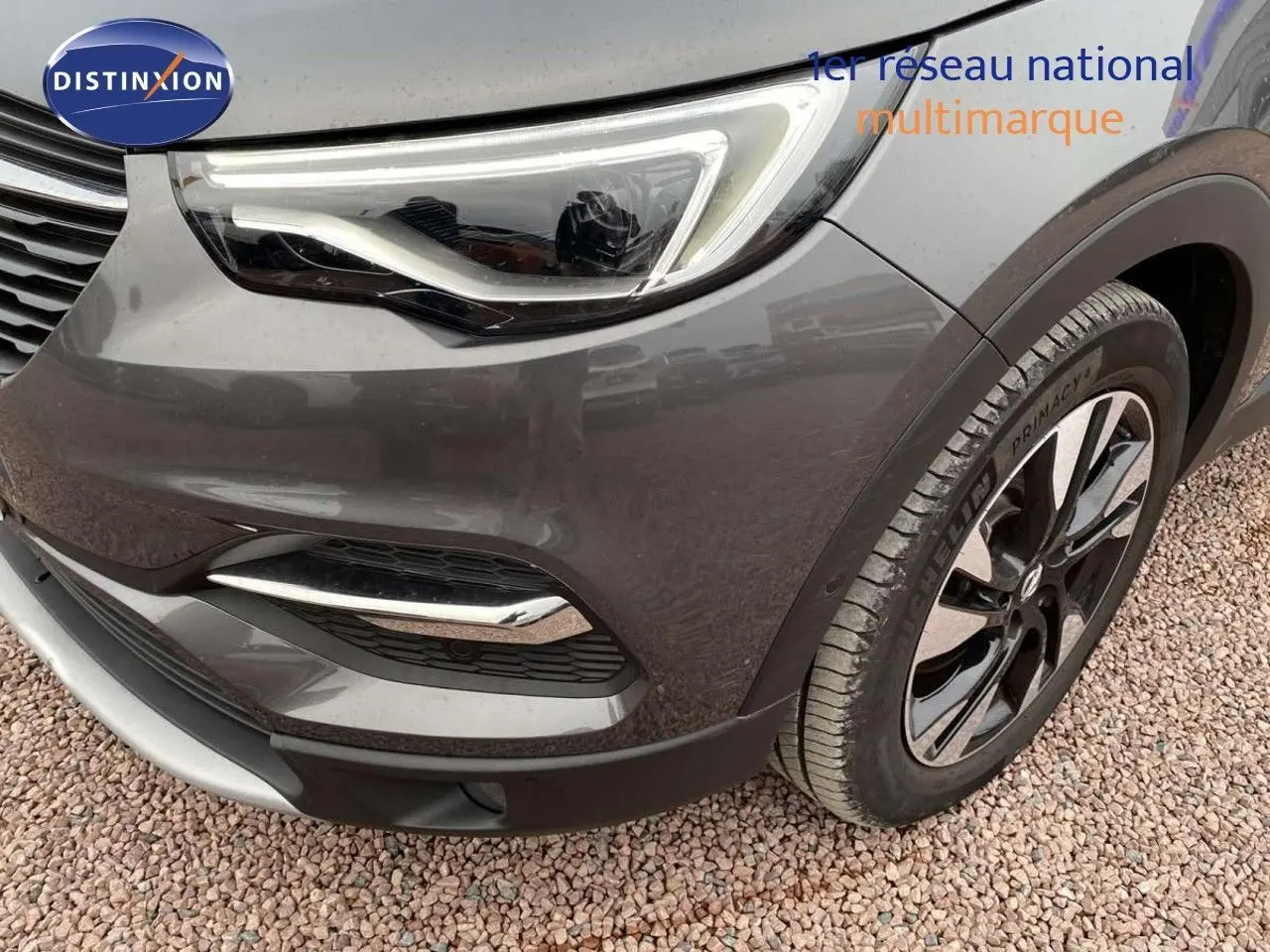 Gros plan sur l'avant droit gris Moai métal de l'Opel Grandland X avec phare LED et jante bicolore.