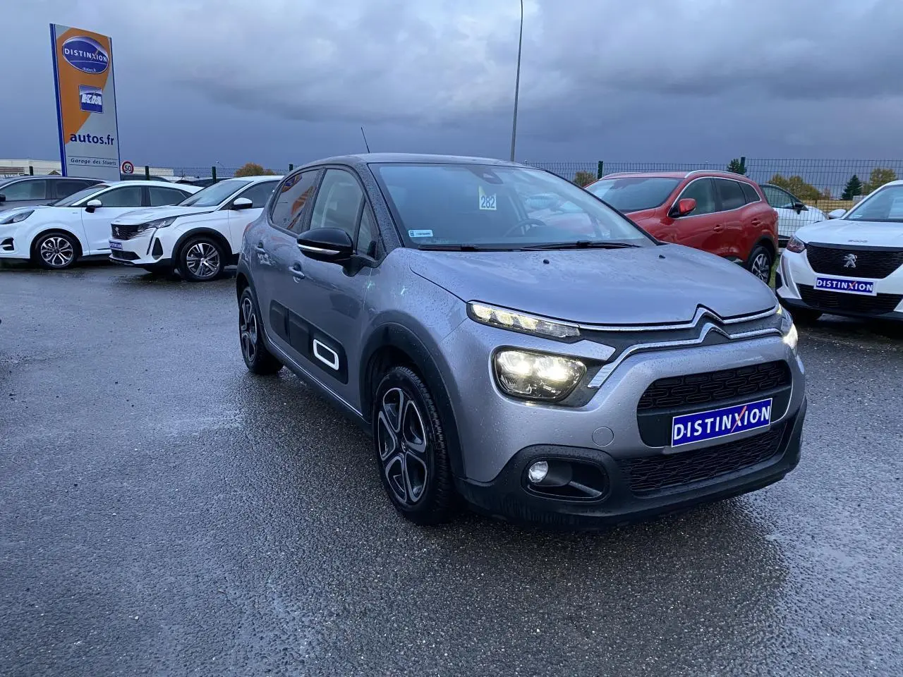 Citroën C3 gris Artense vue 3/4 avant droit sous pluie avec jantes alu 16 pouces et Airbump noirs.