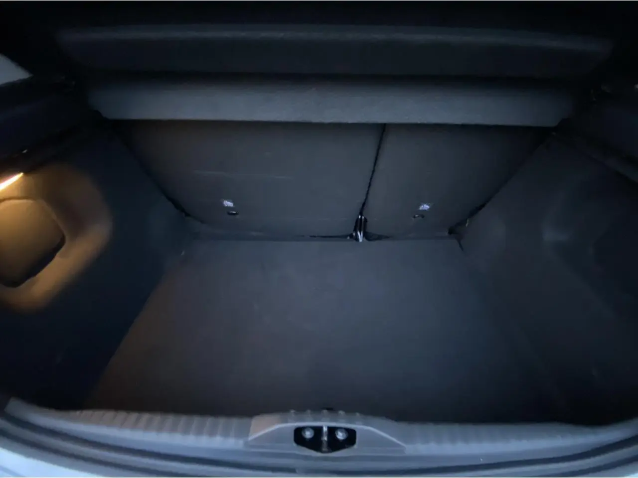 Coffre ouvert de la Citroën C3 1.2 12V Shine gris Artense, montrant un espace de chargement vide et éclairé à gauche.