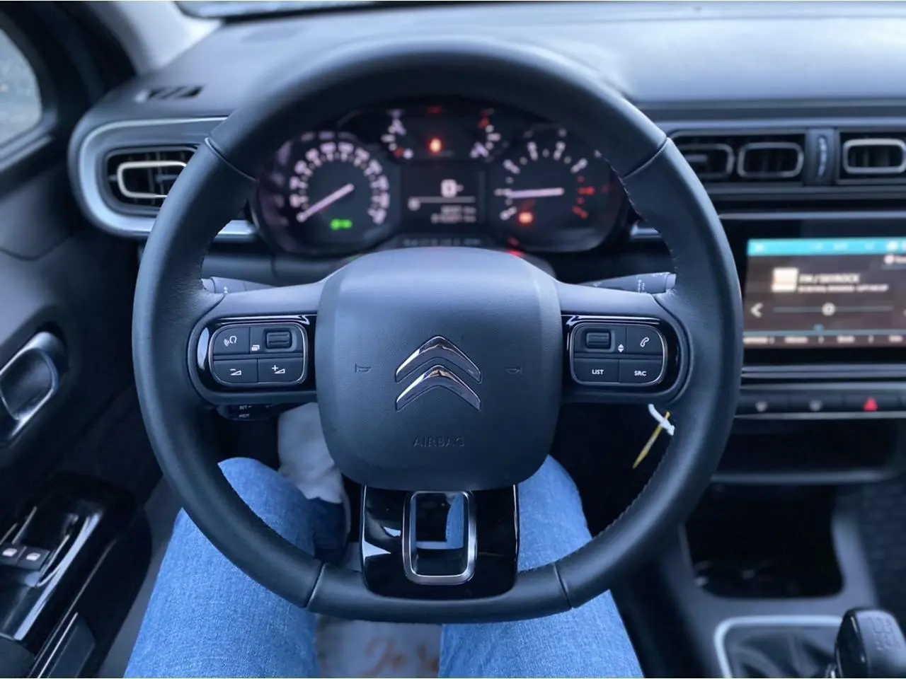 Vue intérieure centrée sur le volant Citroën C3 2022 avec commandes intégrées et tableau de bord numérique.