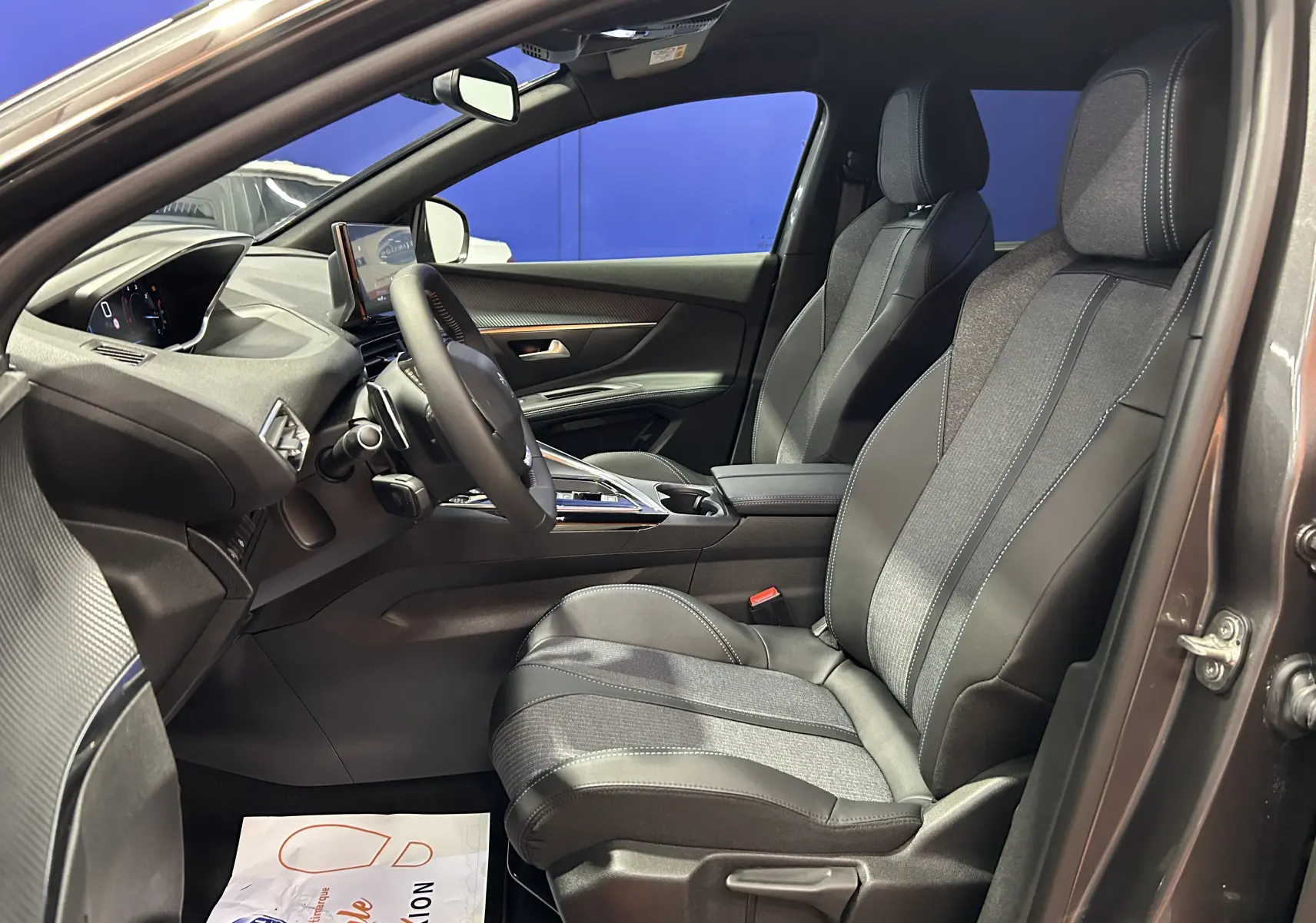 Intérieur avant droit du Peugeot 5008 Gris Platinium 2024, sièges bi-matière et tableau de bord moderne.